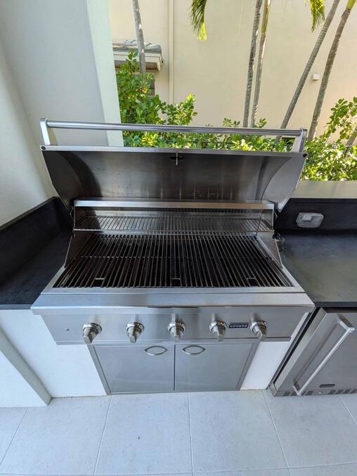 Dirty outdoor gas grill with grease buildup and residue on grates before professional cleaning